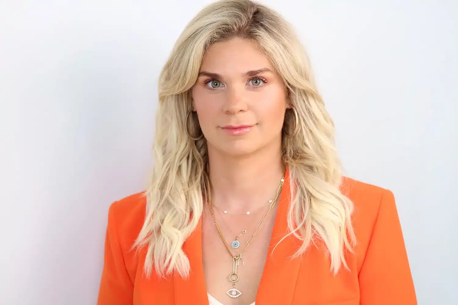 Female leader in a vibrant orange jacket and jewelry, CEO PORTRAIT