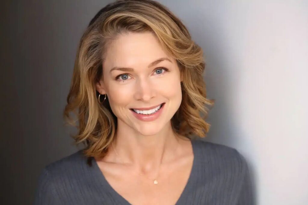 A professional example of corporate headshots in studio, featuring a smiling woman with wavy blonde hair