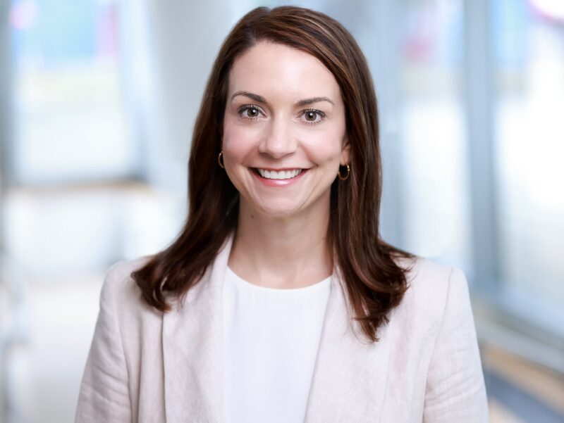 Successful female executive smiling for a professional corporate headshot in a bright office setting
