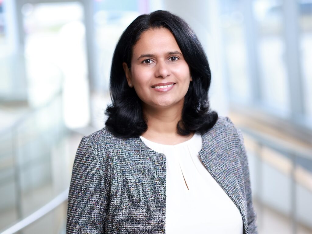 Professional woman smiling for her corporate headshot in a modern office hallway